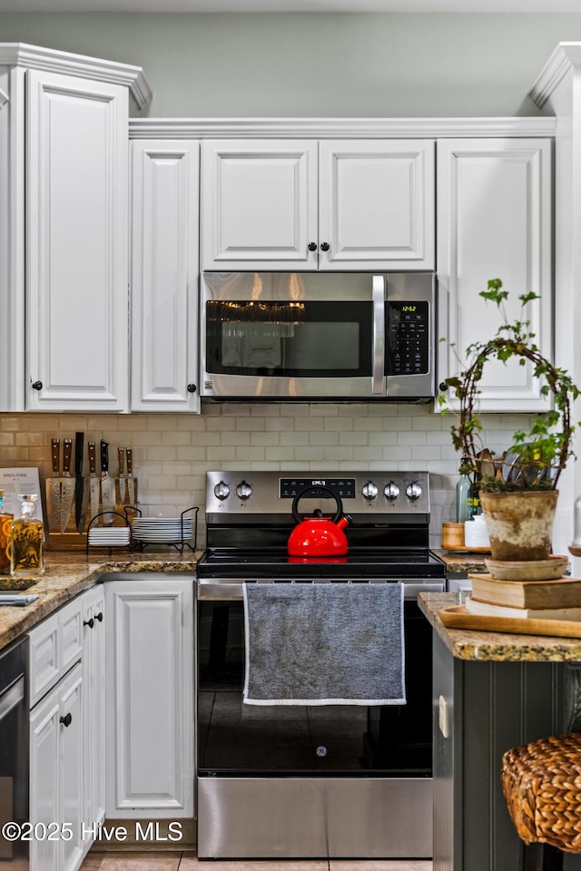 5994 Gray Squirrel Path, Southport, NC 28461 - kitchen featuring appliances with stainless steel finishes, white cabinetry, backsplash, stone countertops, and tile patterned floors