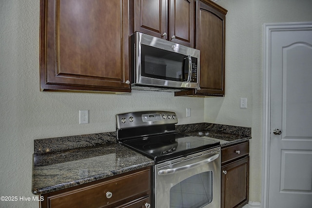103 Whistling Duck Ct, Moyock, NC 27958 - kitchen featuring stainless steel appliances, dark stone countertops, dark brown cabinets, and a textured wall