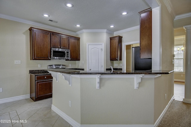 103 Whistling Duck Ct, Moyock, NC 27958 - kitchen with freestanding refrigerator, stainless steel microwave, a breakfast bar area, dark stone counters, and recessed lighting