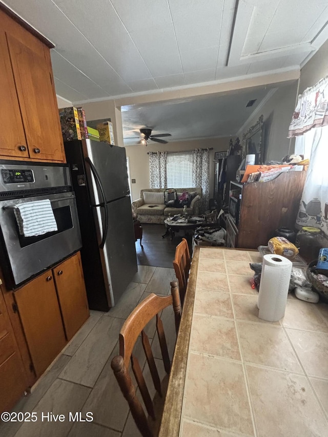 kitchen featuring oven, ceiling fan, tile countertops, brown cabinetry, and freestanding refrigerator