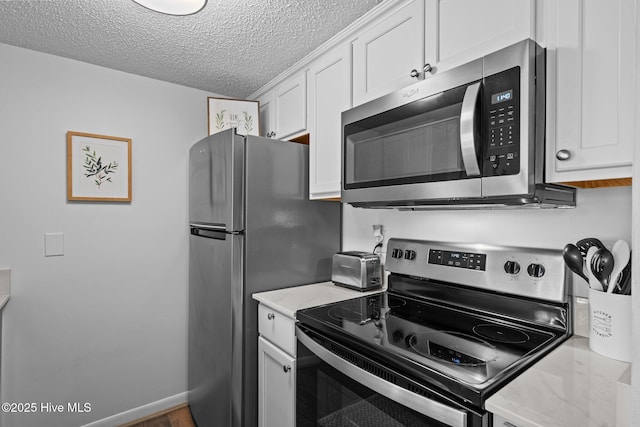 5 Pine Tree Rd Unit 211, Pinehurst, NC 28374 - kitchen featuring appliances with stainless steel finishes, a textured ceiling, white cabinetry, and light stone countertops
