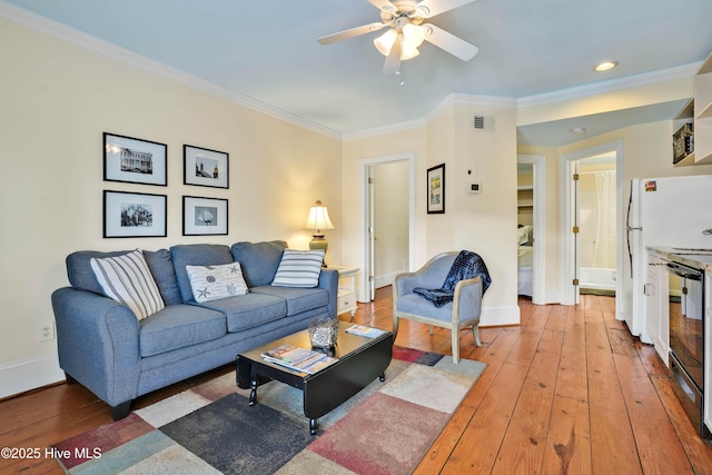 living area with visible vents, baseboards, ornamental molding, a ceiling fan, and light wood-style floors