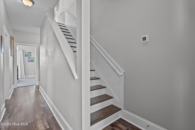staircase featuring wood finished floors and baseboards
