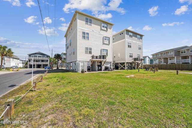 back of house with fence, a yard, and a residential view