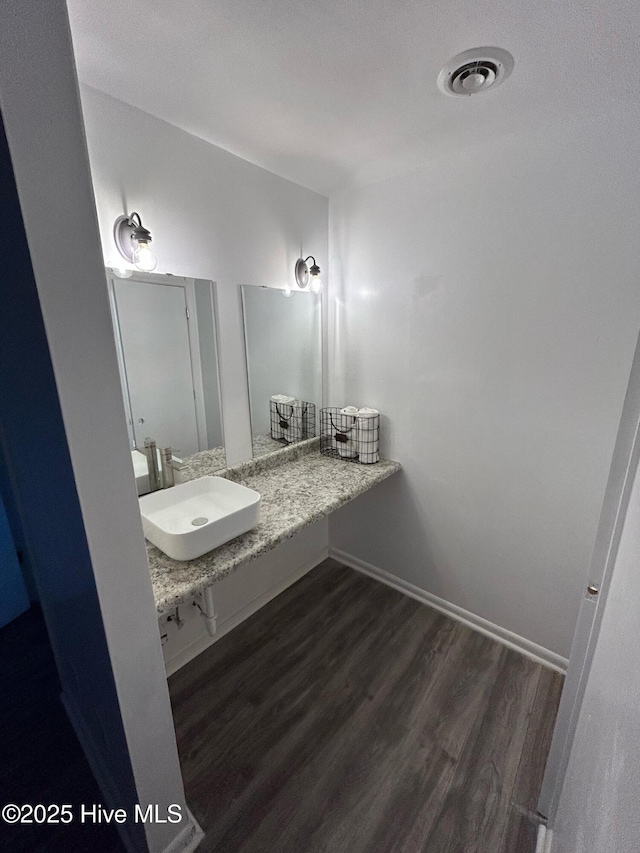 bathroom with baseboards, wood finished floors, a sink, and visible vents