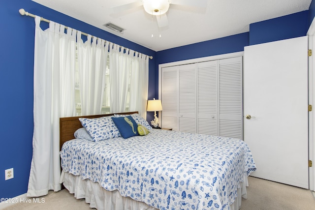carpeted bedroom featuring visible vents, a closet, and a ceiling fan