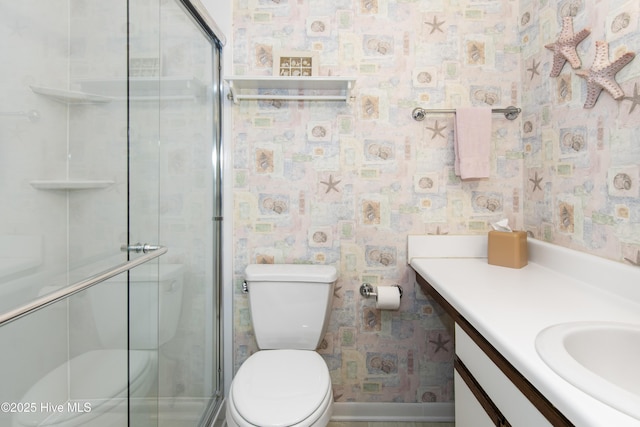 full bathroom featuring a shower stall, vanity, wallpapered walls, and toilet