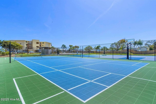 view of tennis court with community basketball court and fence