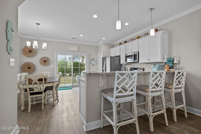 kitchen featuring white cabinets, light wood-type flooring, appliances with stainless steel finishes, and light stone counters
