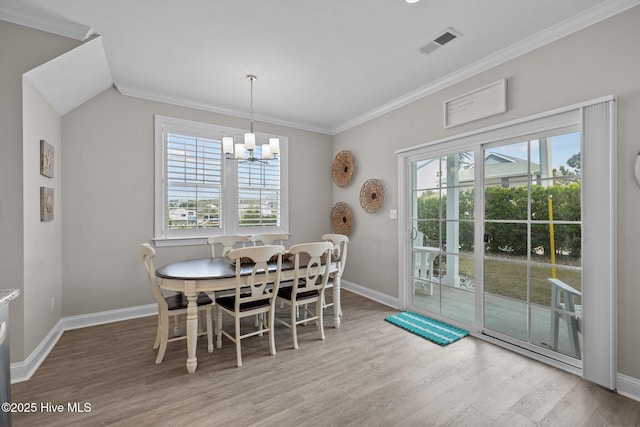 dining room with a chandelier, crown molding, visible vents, baseboards, and wood finished floors