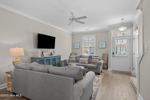 living area with baseboards, a ceiling fan, crown molding, and light wood-style flooring