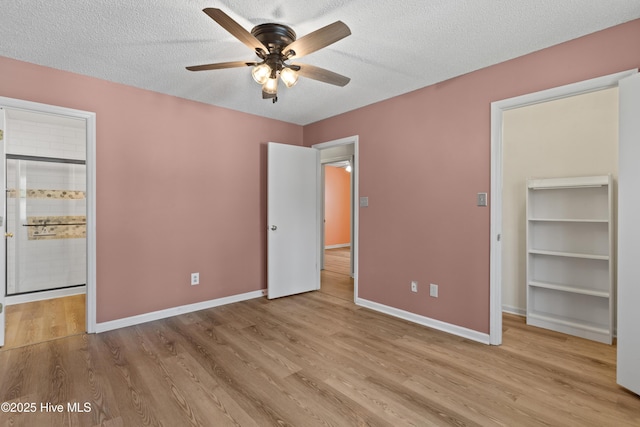 unfurnished bedroom featuring baseboards, wood finished floors, ensuite bathroom, and a textured ceiling