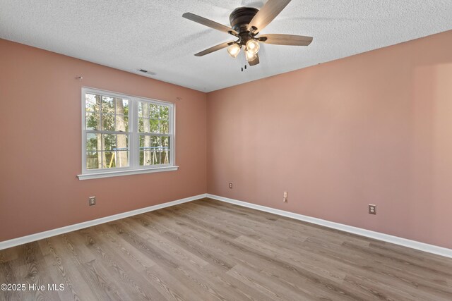 unfurnished room featuring a textured ceiling, baseboards, wood finished floors, and a ceiling fan
