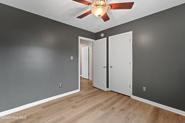 unfurnished bedroom with baseboards, a textured ceiling, ceiling fan, and light wood-style flooring