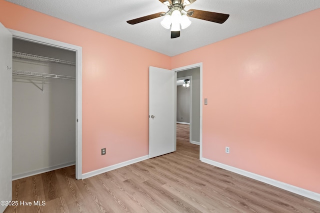 unfurnished bedroom with baseboards, a textured ceiling, a ceiling fan, a closet, and wood finished floors