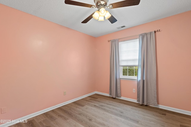 unfurnished room featuring a textured ceiling, baseboards, visible vents, light wood-style floors, and ceiling fan