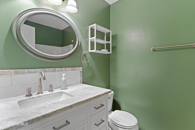 bathroom featuring decorative backsplash, toilet, and vanity