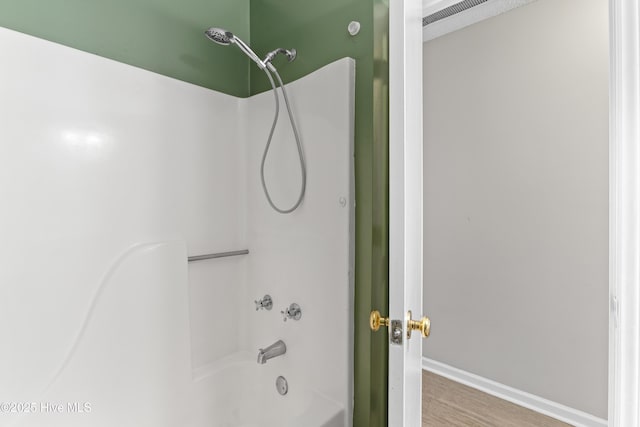 full bath with shower / washtub combination, wood finished floors, and baseboards