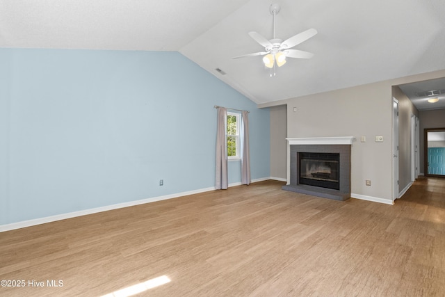 unfurnished living room with vaulted ceiling, ceiling fan, a brick fireplace, visible vents, and wood finished floors