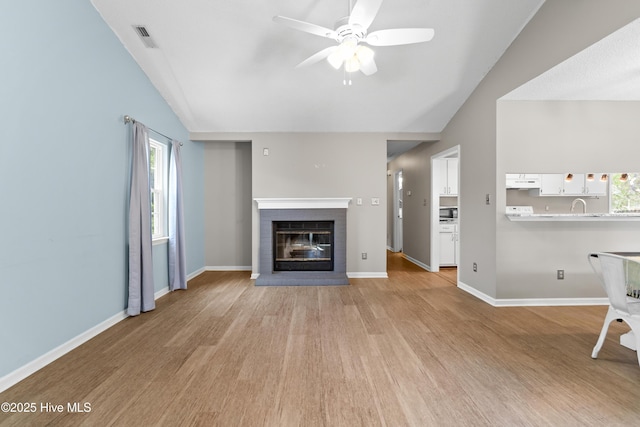 unfurnished living room featuring visible vents, a brick fireplace, light wood finished floors, ceiling fan, and lofted ceiling