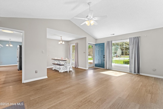 interior space featuring a textured ceiling, baseboards, wood finished floors, lofted ceiling, and ceiling fan with notable chandelier