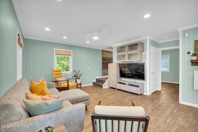 living area featuring crown molding, a ceiling fan, baseboards, and light wood-type flooring