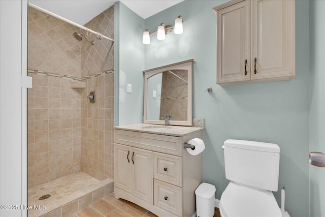 bathroom with vanity, toilet, and tiled shower