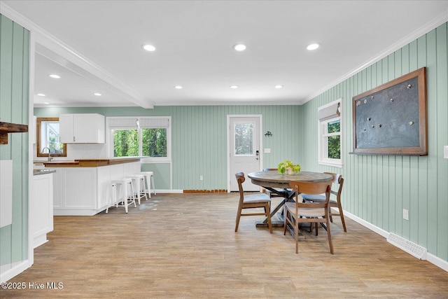 dining area with crown molding, light wood-style floors, and baseboards