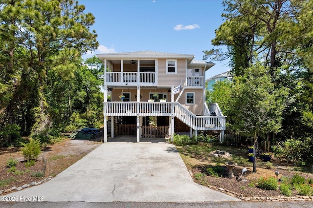 view of front of home featuring covered porch, driveway, a ceiling fan, stairway, and a balcony