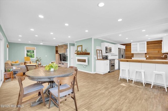 dining room featuring crown molding, recessed lighting, and light wood-type flooring