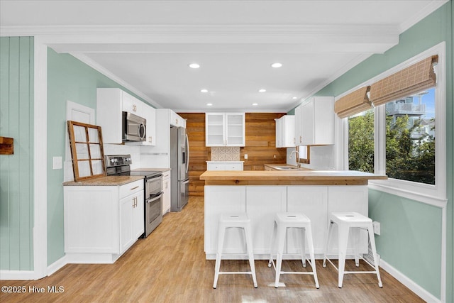 kitchen featuring decorative backsplash, a peninsula, baseboards, recessed lighting, and appliances with stainless steel finishes