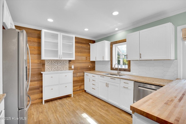 kitchen with decorative backsplash, glass insert cabinets, white cabinetry, a sink, and stainless steel appliances