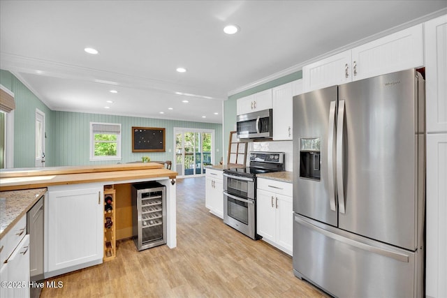 kitchen featuring stainless steel appliances, ornamental molding, beverage cooler, and white cabinetry