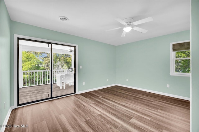 spare room featuring a ceiling fan, a wealth of natural light, and wood finished floors