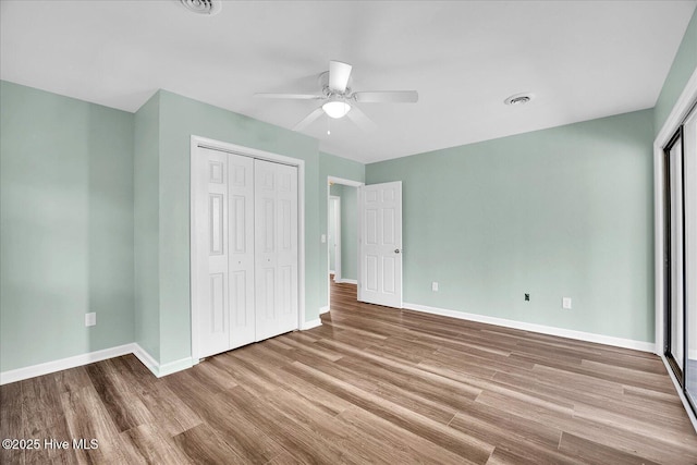 unfurnished bedroom with baseboards, wood finished floors, and a closet