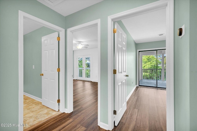 hallway featuring baseboards, wood finished floors, and a healthy amount of sunlight