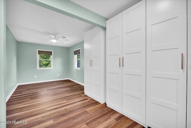 unfurnished bedroom with a ceiling fan, baseboards, and wood finished floors