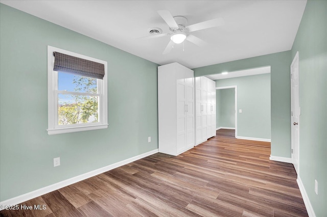 unfurnished bedroom with a ceiling fan, baseboards, wood finished floors, visible vents, and a closet