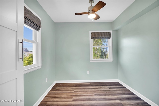 empty room featuring baseboards, plenty of natural light, a ceiling fan, and dark wood-style floors
