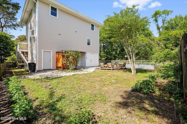 rear view of property featuring fence, a wooden deck, a yard, and stairway