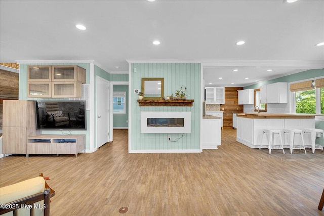 living area with crown molding, recessed lighting, light wood-style flooring, and a fireplace