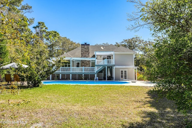 7001 Robert Ruark Dr SE, Southport, NC 28461 - rear view of house featuring french doors, a wooden deck, an outdoor pool, and a yard