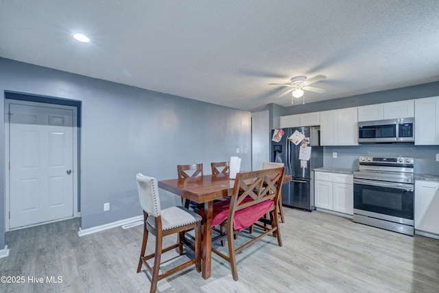 dining area with light wood finished floors, a textured ceiling, baseboards, and ceiling fan