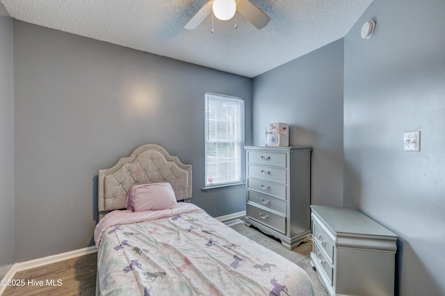 bedroom with ceiling fan, a textured ceiling, light wood finished floors, and baseboards