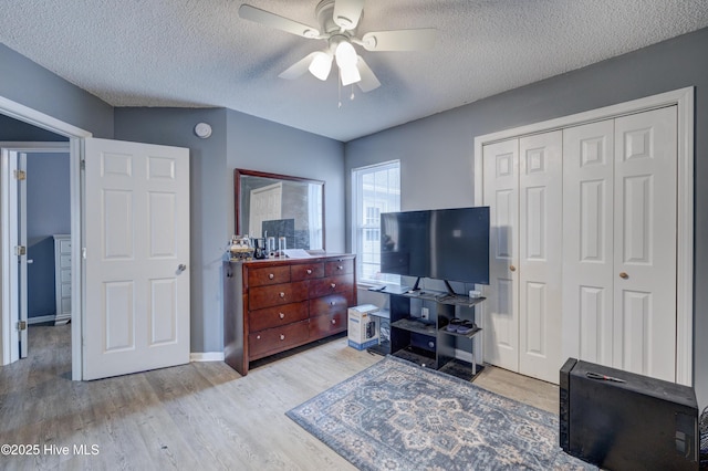 bedroom featuring ceiling fan, a textured ceiling, a closet, wood finished floors, and baseboards