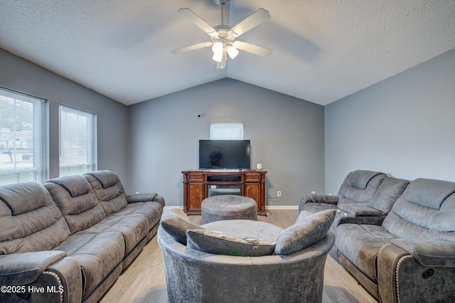 living area featuring a ceiling fan, vaulted ceiling, light wood-style floors, and a textured ceiling