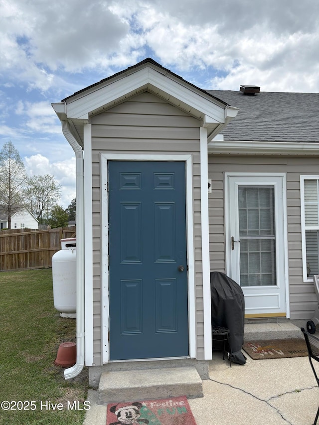 view of exterior entry featuring a yard and fence