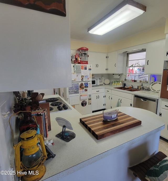kitchen featuring white appliances, white cabinetry, light countertops, and a sink