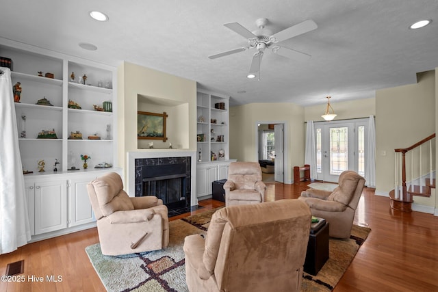 living area featuring stairway, visible vents, light wood-style flooring, and a premium fireplace