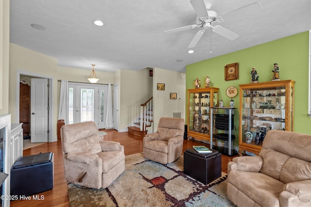 living area with recessed lighting, ceiling fan, wood finished floors, and stairway